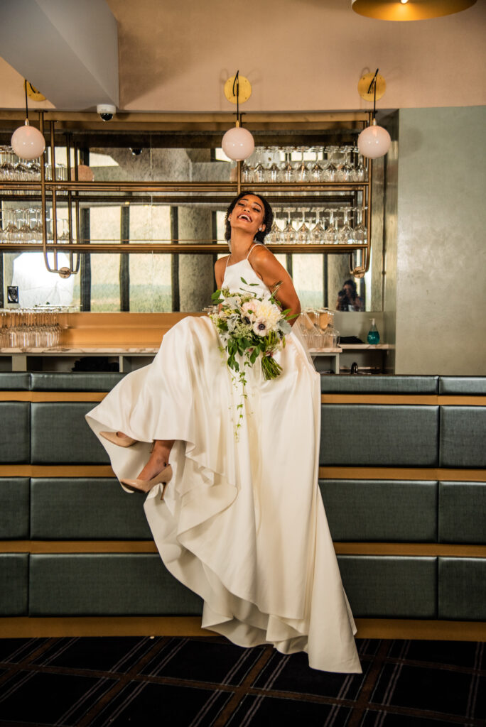 woman posing in front of bar in white satin wedding dress