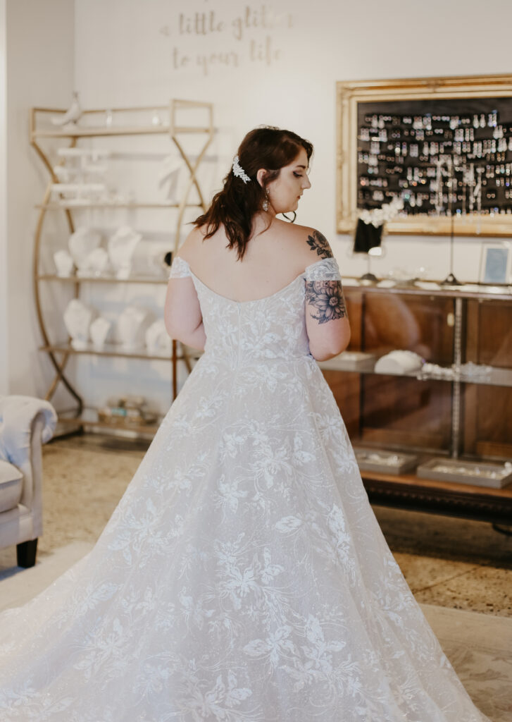 Back of a woman wearing a lace plus size wedding dress with a flowing train wedding shoppe berkley mi