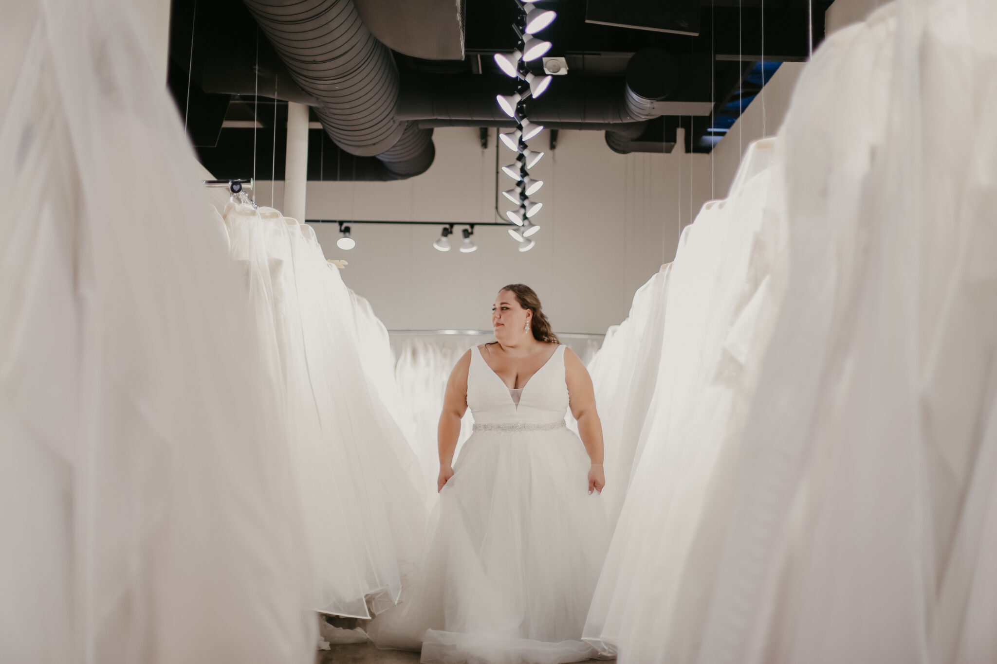 woman walking down aisle of wedding gowns bridal shop berkley mi
