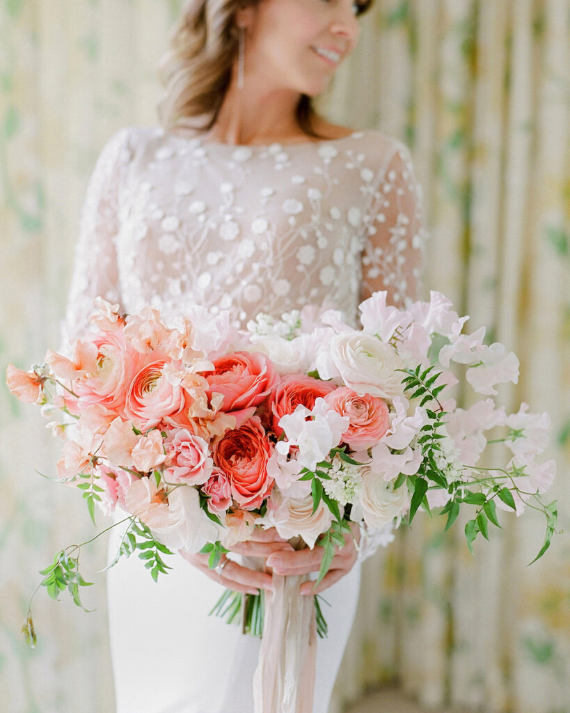 bouquet of pink and white roses held by a women in a wedding dress with lace overlay
