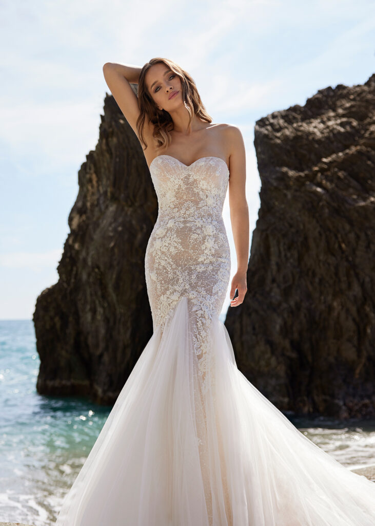 woman in mermaid luxury wedding gown standing on beach sand