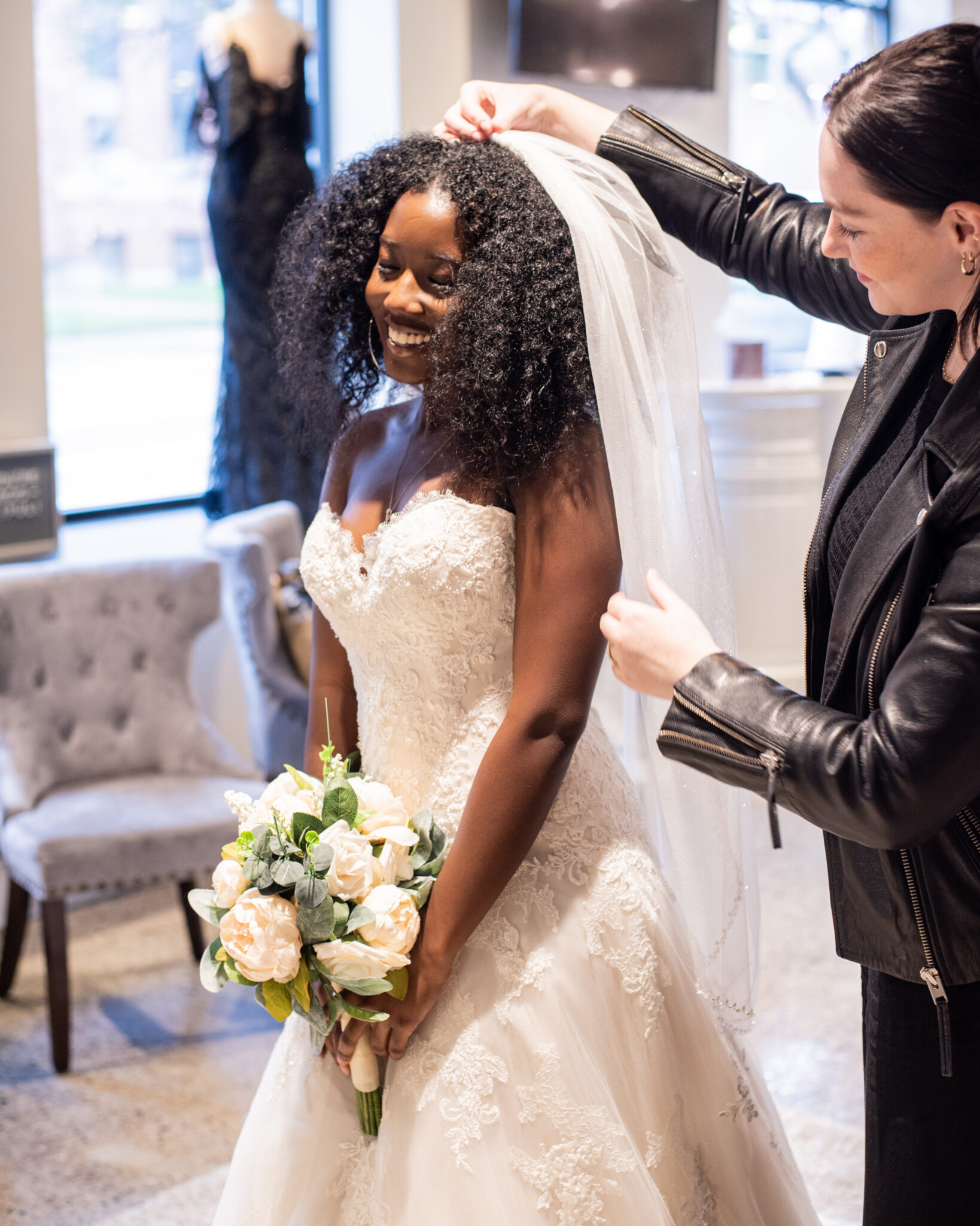 woman trying on white floral bridal gown while holding bouquet