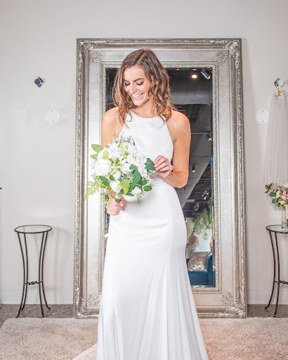 happy bride holding bouquet of flowers and wearing white sheath wedding dress