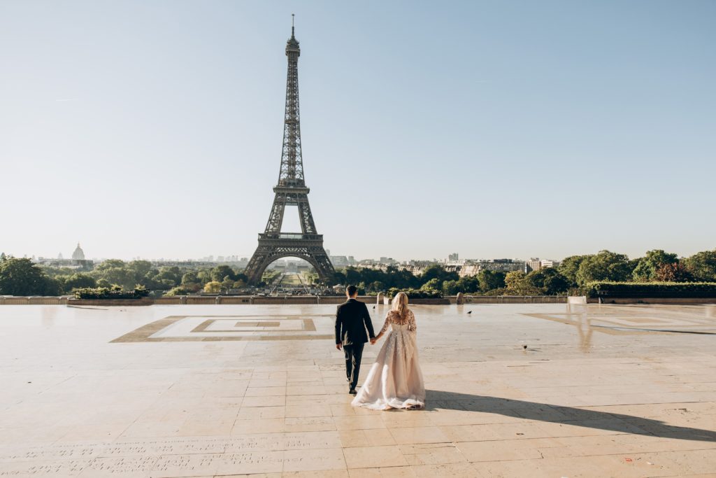 A couple holding hands with the Eiffel tower in the background