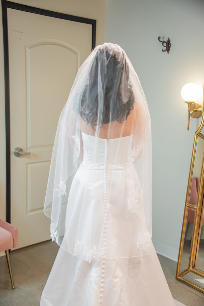 A woman wearing a bridal veil facing away from the camera