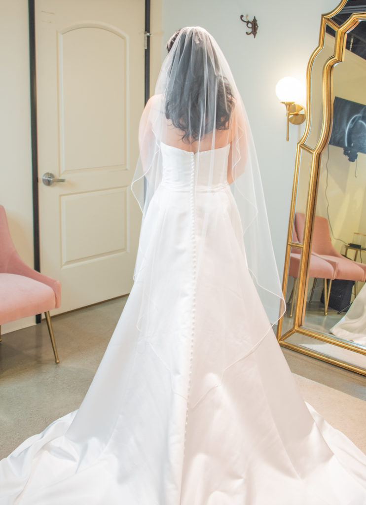 A picture of a woman in a bridal dress with her back to the camera