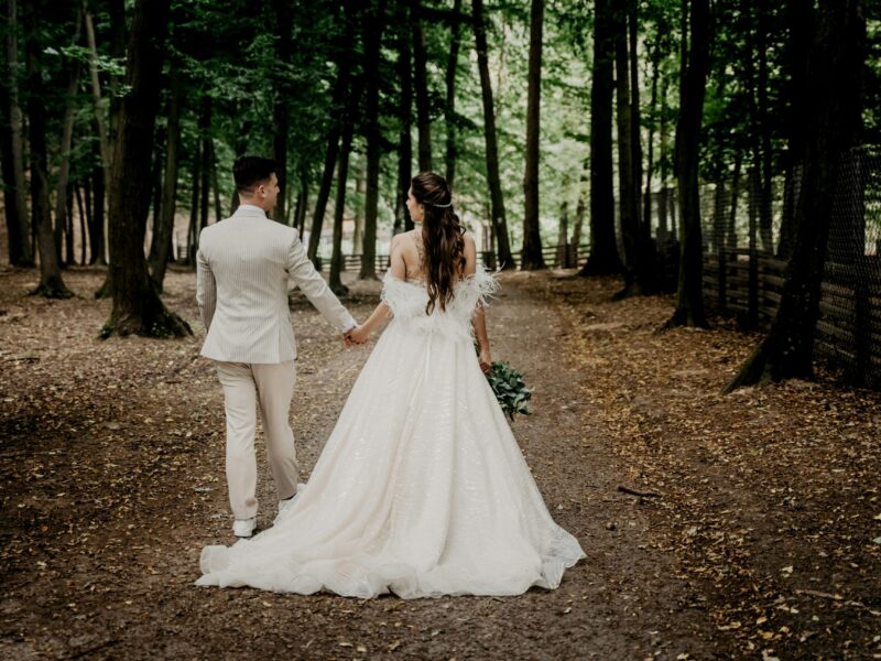 A bride and groom walking in a forest.