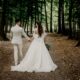 A bride and groom walking in a forest.