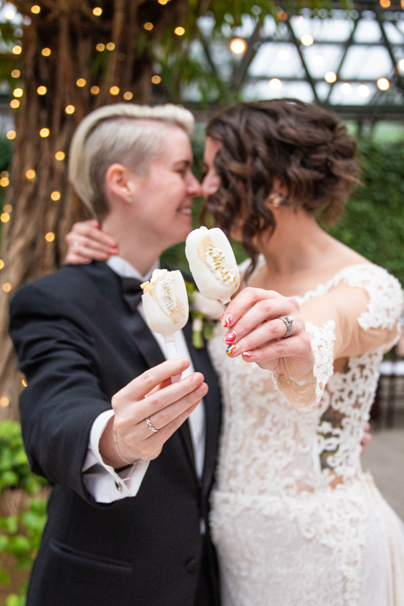 wedding couple holding out treat on a stick