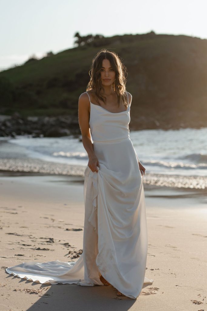 woman in white bridal gown standing on beach shore