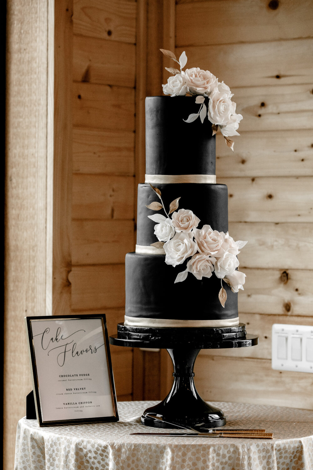 A 3-tier black wedding cake with white roses.