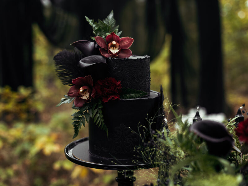 A unique and beautiful dark wedding cake with flowers.