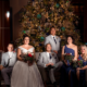 bride, groom and their guests posing in front of christmas tree