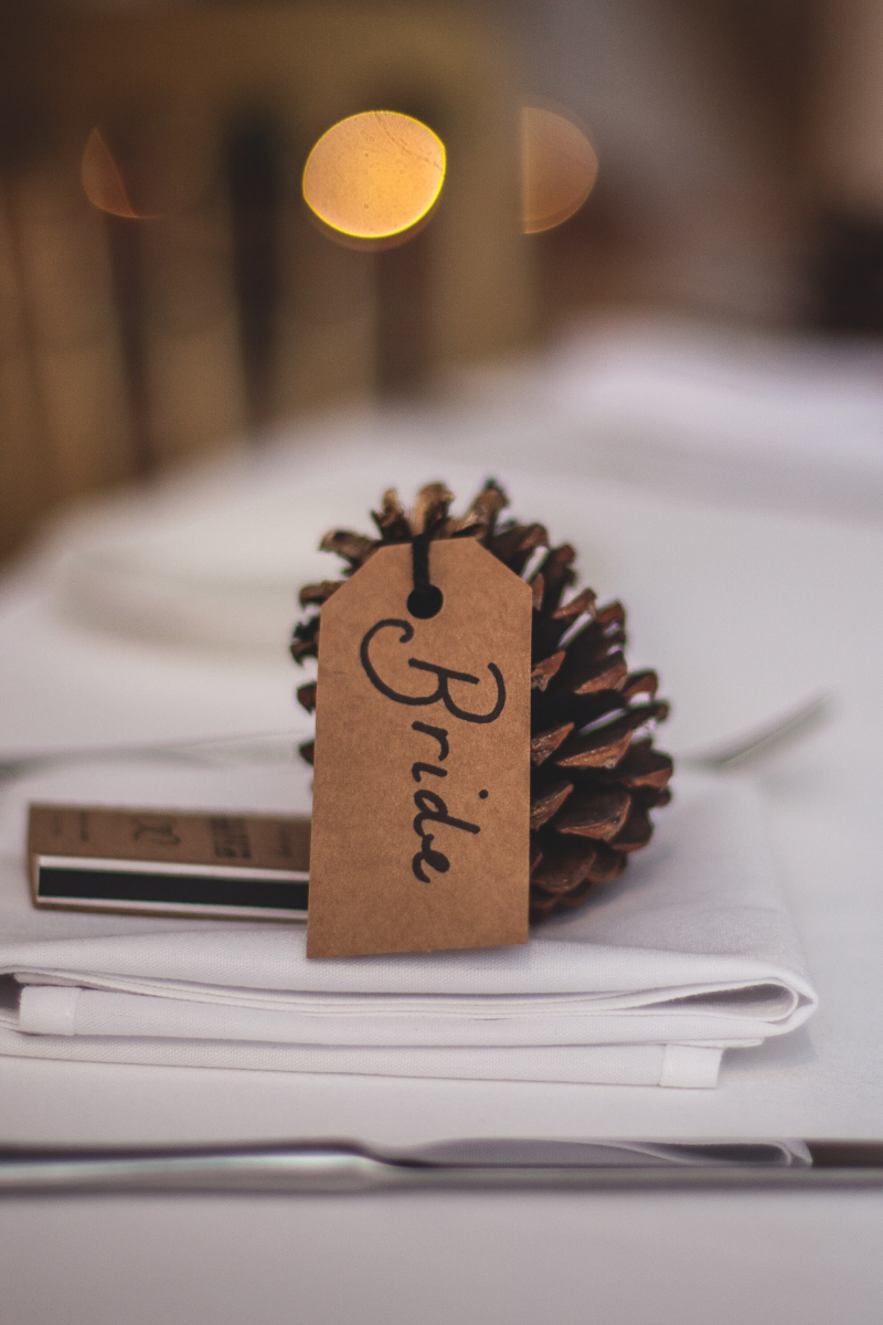pinecone set on dinner table with tag reading "Bride"