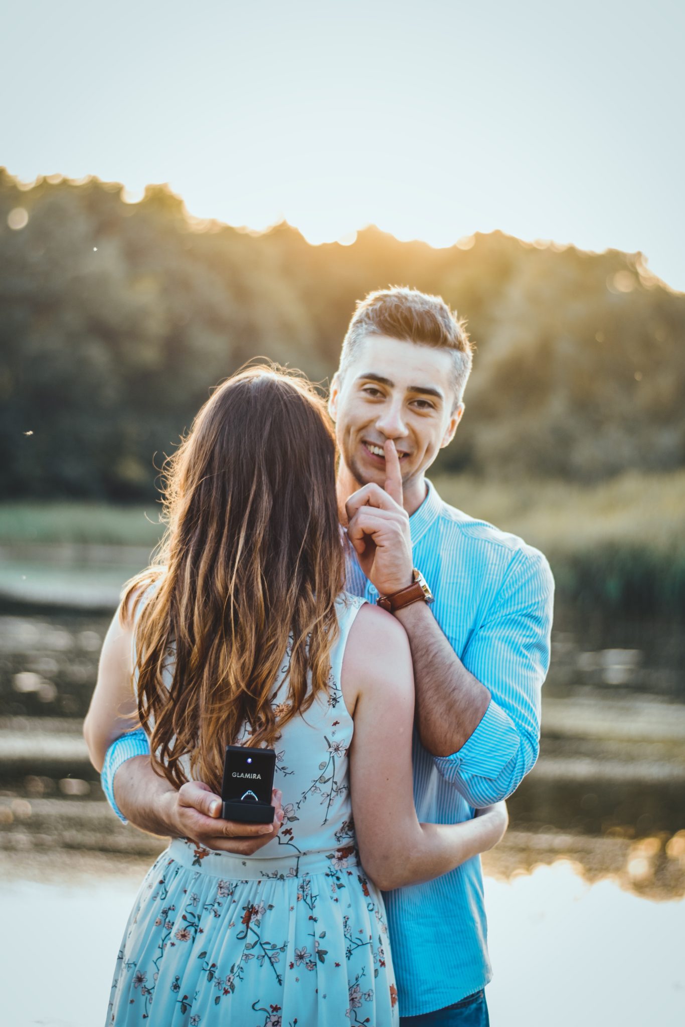 Man hugging woman and showing a wedding ring behind