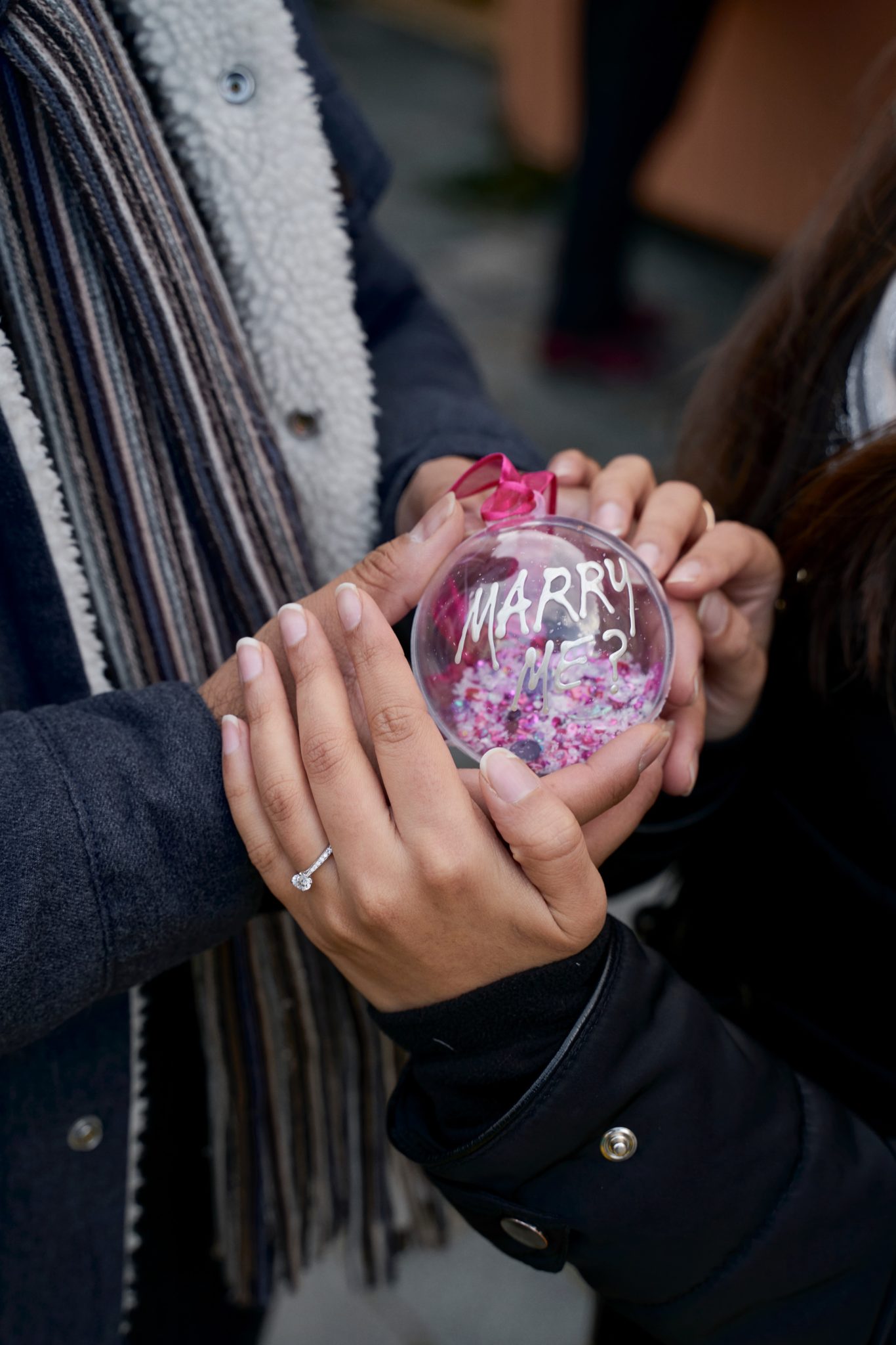 woman and man holding ornament saying "Marry Me?"