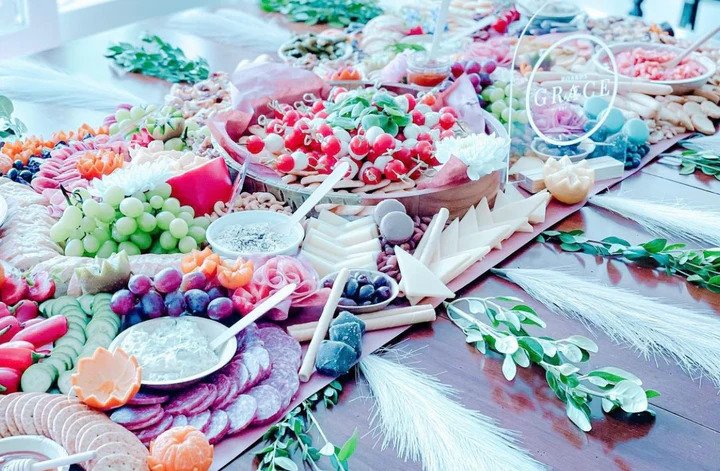 A charcuterie table setting with fruits, meats, vegetables, and crackers from Boards with Grace