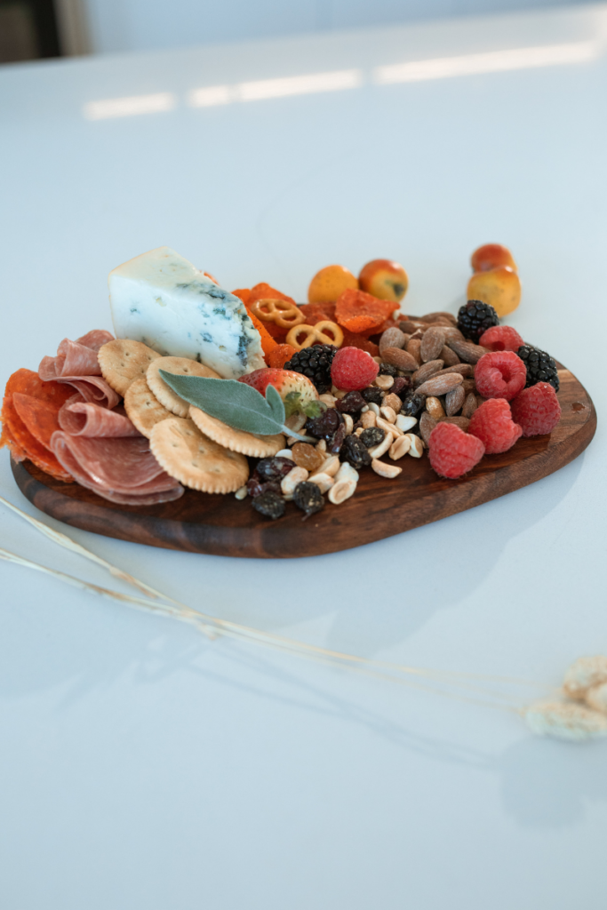 a finger food charcuterie board with crackers, meat, nuts, cheese, and berries