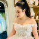Beautiful off-the-shoulder blush lace floral wedding gown, worn by a brunette model at The Wedding Shoppe in Berkley, Michigan.