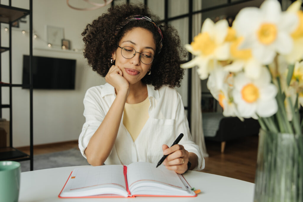 woman with a pen and notebook planning a bridal shower