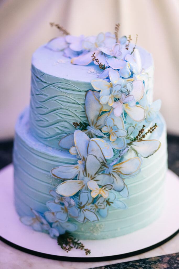 blue wedding cake with butterflies and floral accents for fairytale wedding
