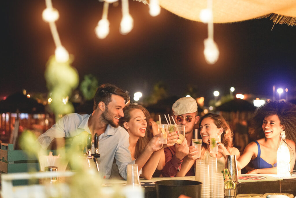 friends having drinks at a beach-themed wedding rehearsal dinner