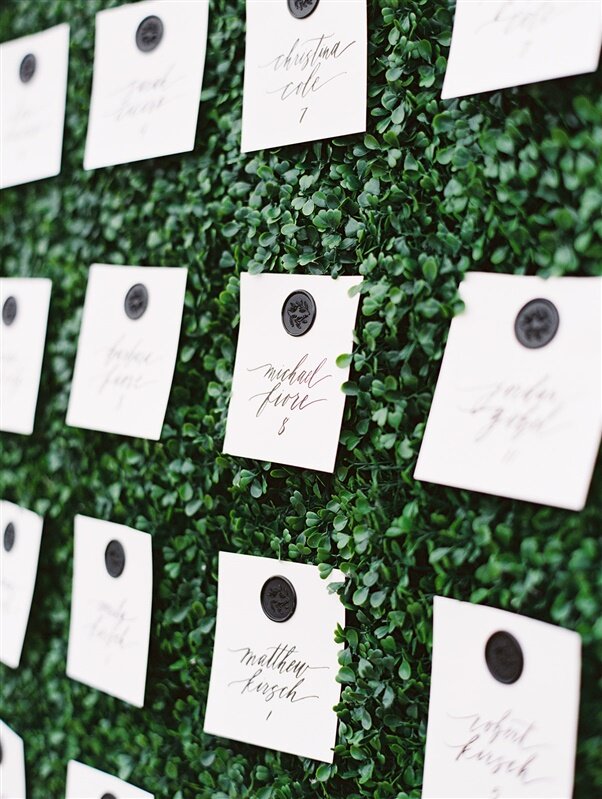 natural greenery wall with escort cards for wedding seating