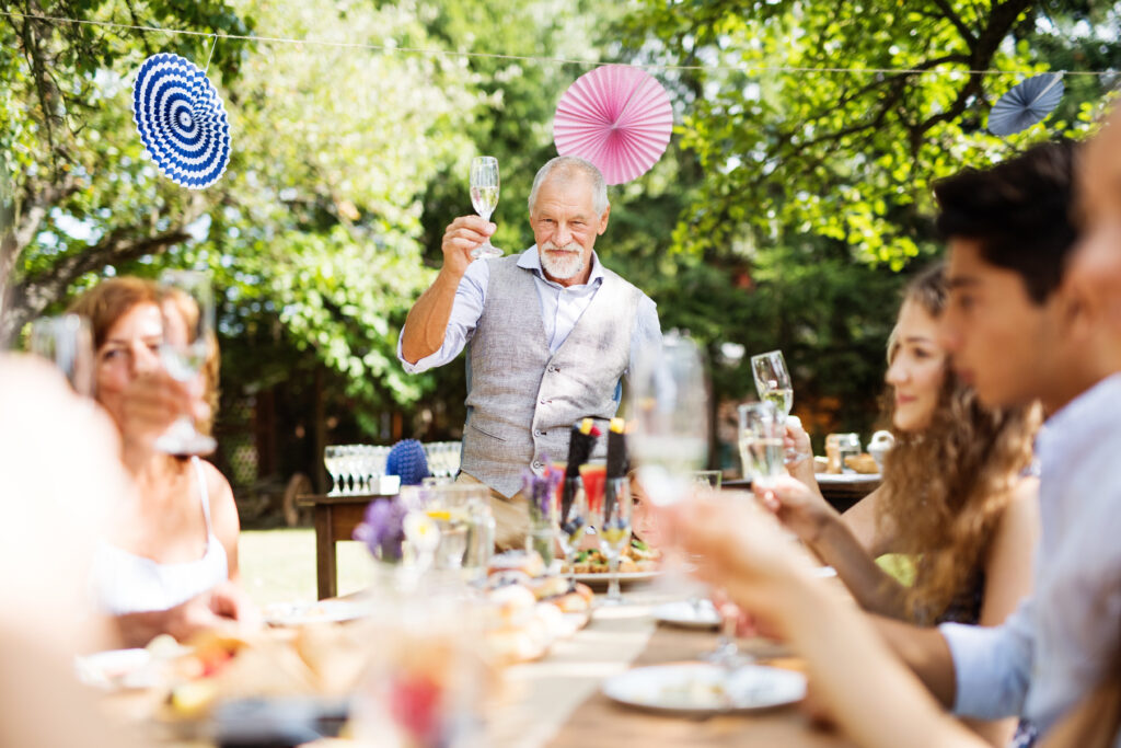 people raising their glasses for a toast or speech at a wedding rehearsal dinner