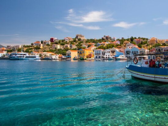 greek islands with crystal blue water and a boat in front of colorful houses honeymoon idea