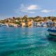 greek islands with crystal blue water and a boat in front of colorful houses honeymoon idea