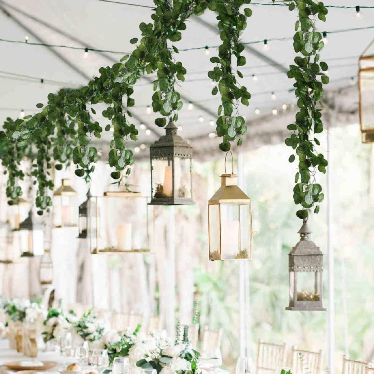 Artificial garland with lanterns hanging above wedding reception setting.
