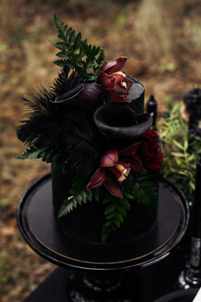 wedding cake decorated with black frosting and dark flowers