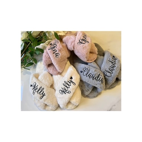 three pair of fluffy, slipper sandles. On each pair of sandles is a name embroidered in black script.