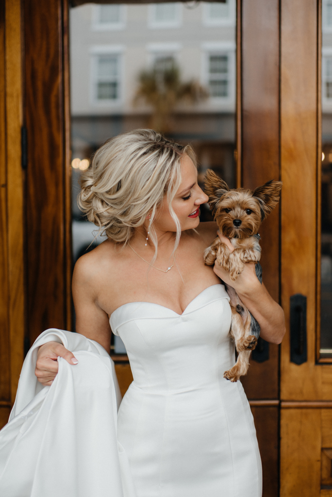 a bride holding a small dog on her wedding day