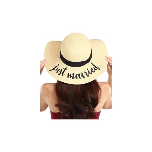 Back side of a woman wearing a beige floppy beach hat. The hat has a black band around the base and the words "just married" printed on the back of the brim.