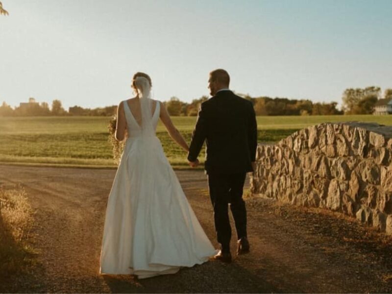 married couple walking down a road as the sun sets in front of them