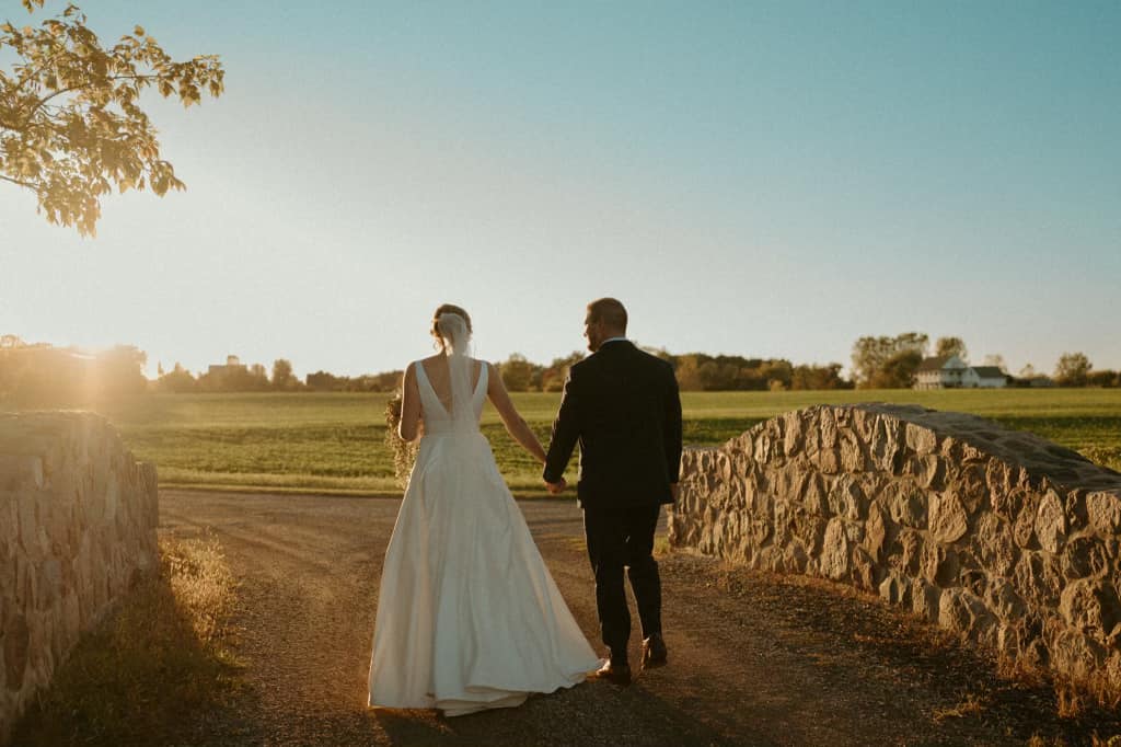 married couple walking down a road as the sun sets in front of them