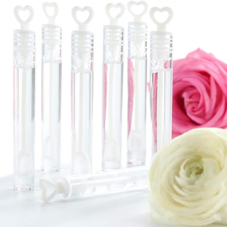 Six clear bubble containers with heart shaped wands. Two roses are laying on the table nearby.