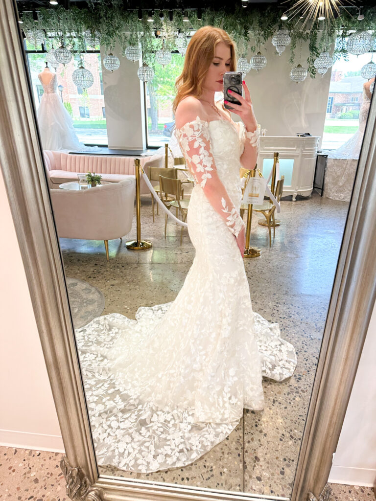 Redheaded bride wearing off the shoulder lace wedding dress with cathedral length veil.