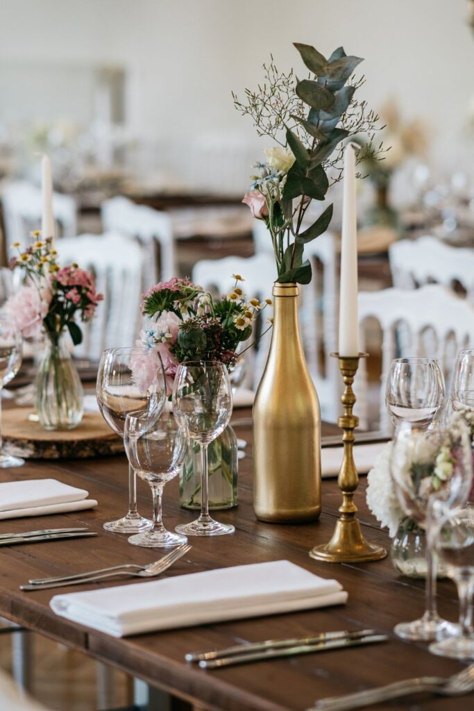 beautiful table setting dressed with glasses, a gold bottle, and a gold candle holder for a victorian wedding