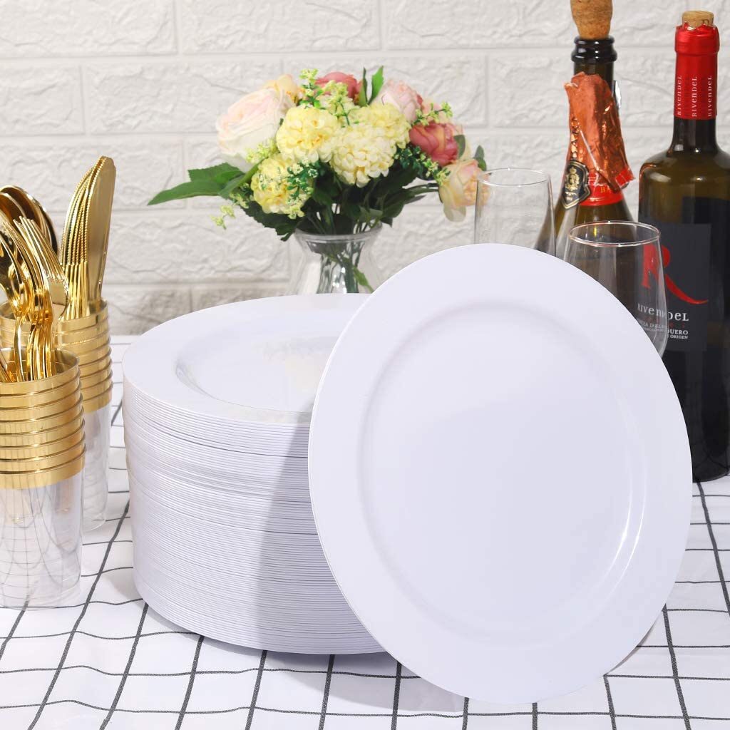 Stack of disposable white plates in the middle of a table. Nearby are gold eating utensils and bottles of wine.