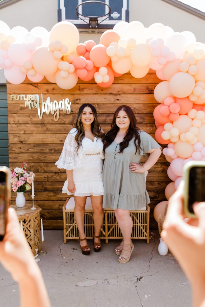 bride and bridesmaid underneath a balloon arch at a homey bridal shower
