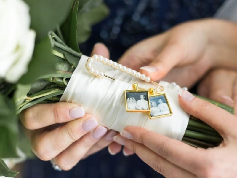 Alexa, a The Wedding Shoppe Bride, holding a bouquet of white flowers bound together along with a safety pin with pictures attached