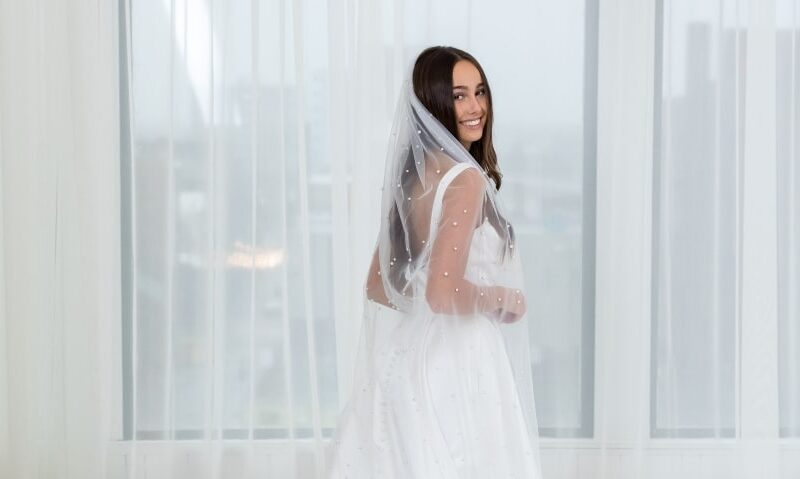 bride wearing a wedding dress and a white pearl veil as her "something borrowed"