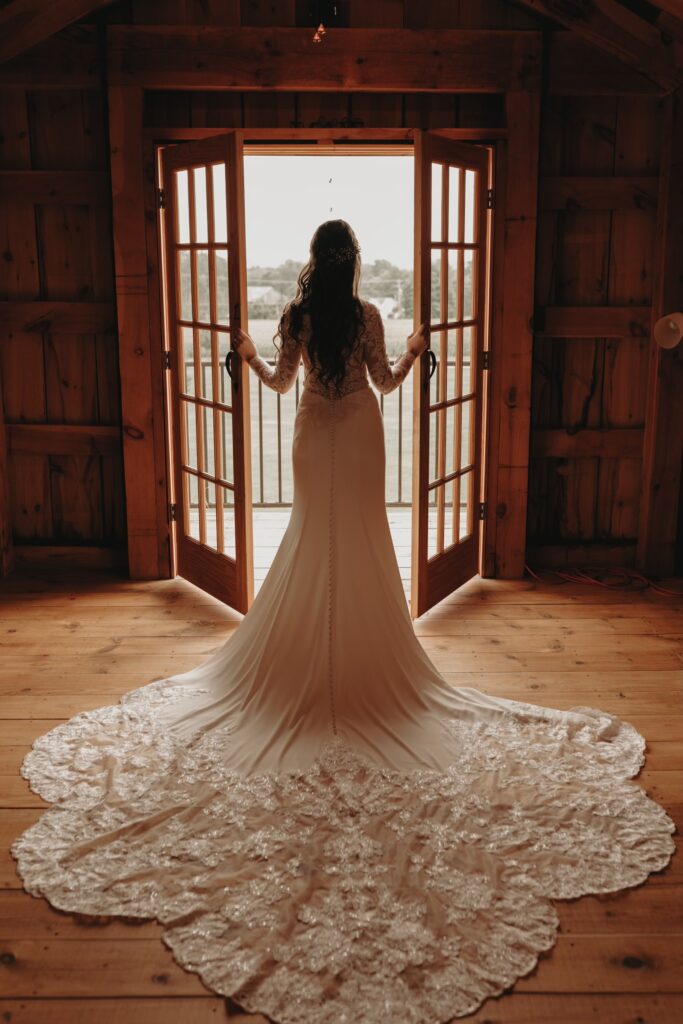 Carissa, a The Wedding Shoppe bride, standing in front of double doors looking out