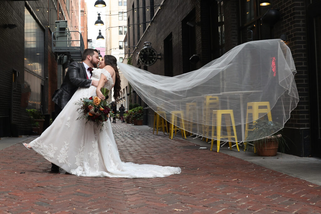 new husband and wife on a brick street in Michigan with a long veil