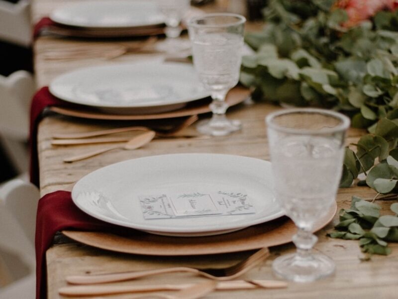 rustic wedding table setting with plates and red cloth napkins