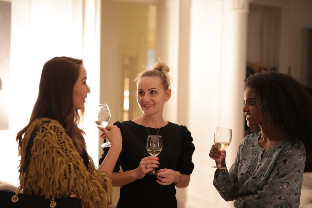 three women having a conversation each with a glass of white wine