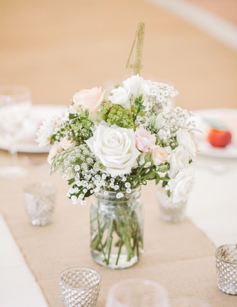 a mason jar centerpiece filled with water and flowers for a DIY wedding