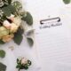 a table with a wedding checklist clipboard next to a bouquet of flowers